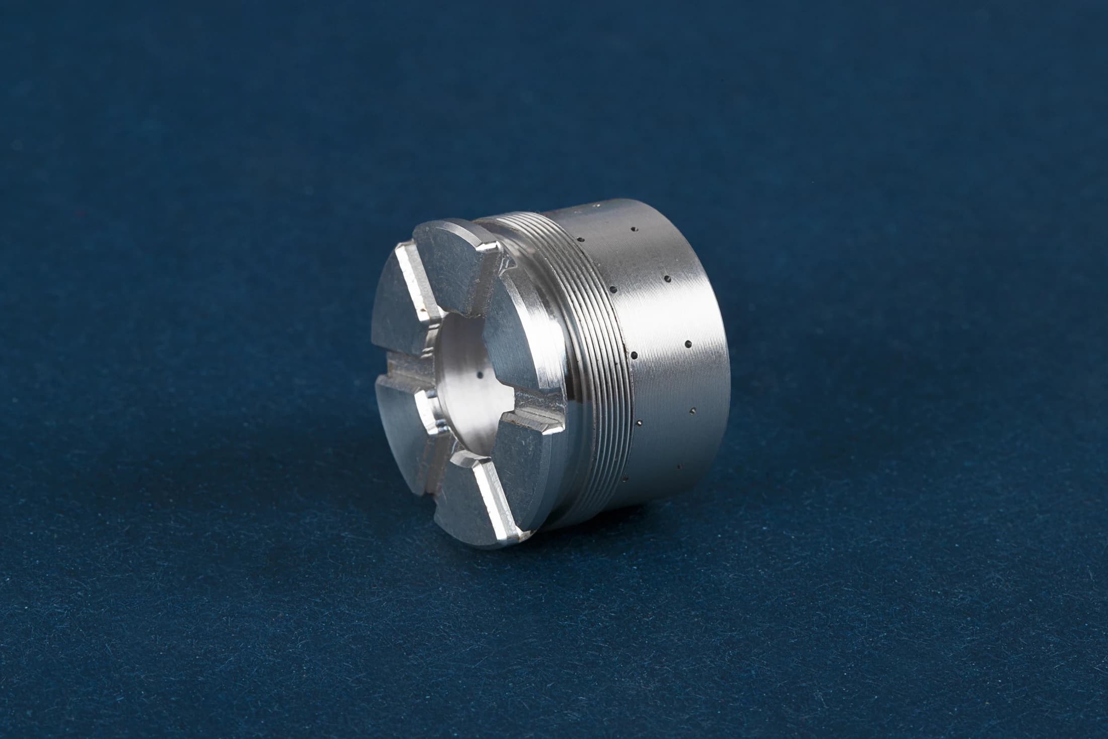 Cylindrical part with end slots on a dark blue background