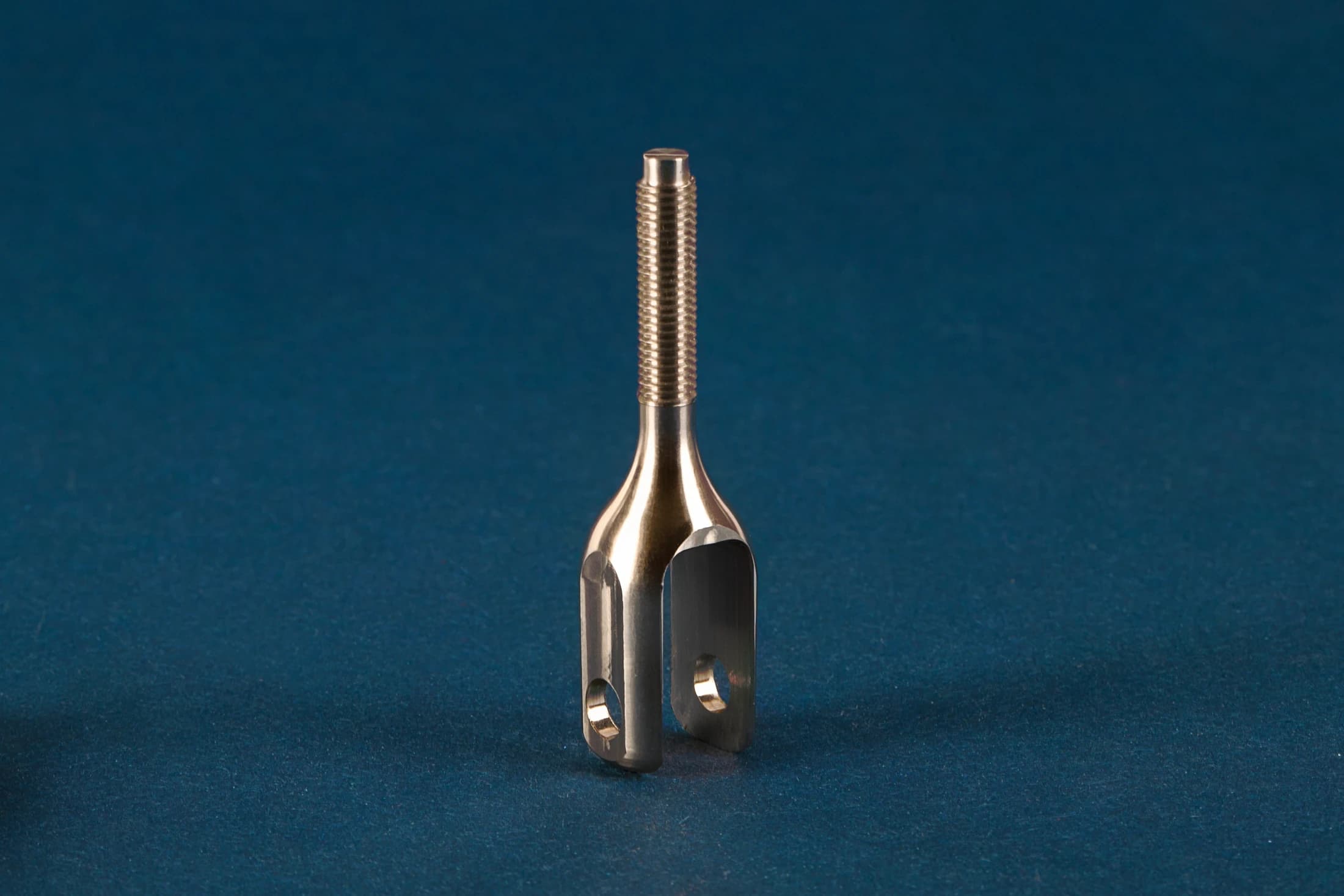 Fork-shaped part with a thread on a dark blue background