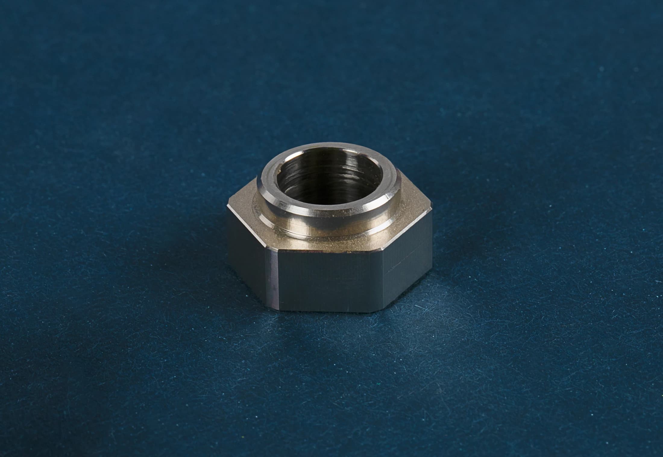 Hexagonal part with an internal thread on a dark blue background